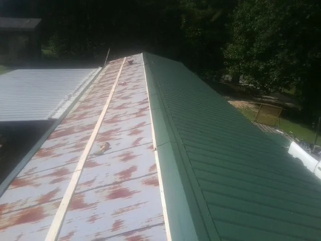 Old rusted panels beside newly installed green metal roofing — Wind Damage Roof Repair by Roofing Brothers in Marion Center
