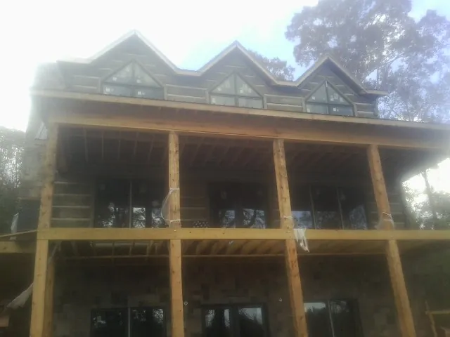 Dormers and porch framing on a large log home under construction — Roof Coating work by our crew in Marion Center