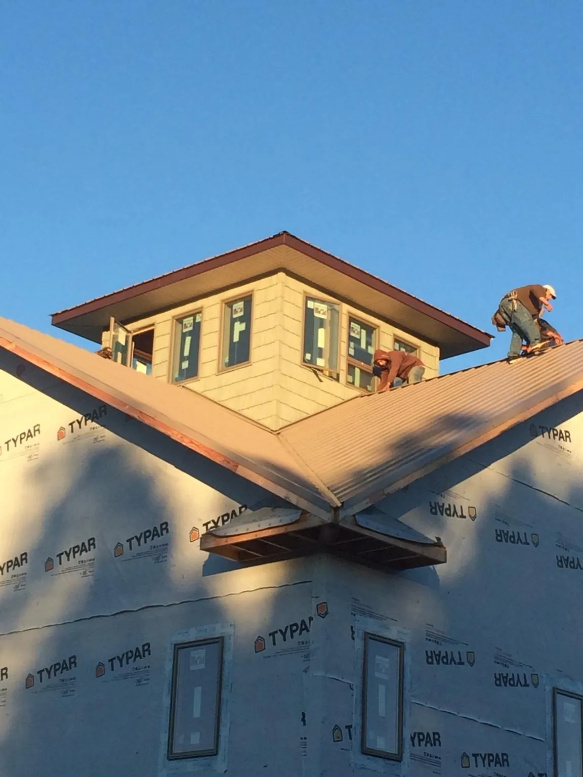 Roofers working around a rooftop cupola on a new metal roof at sunset — Roof Waterproofing in Marion Center by Roofing Brothers